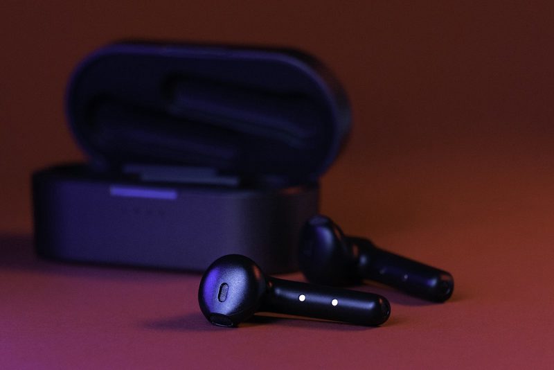 Stemmed wireless earbuds in front of their case