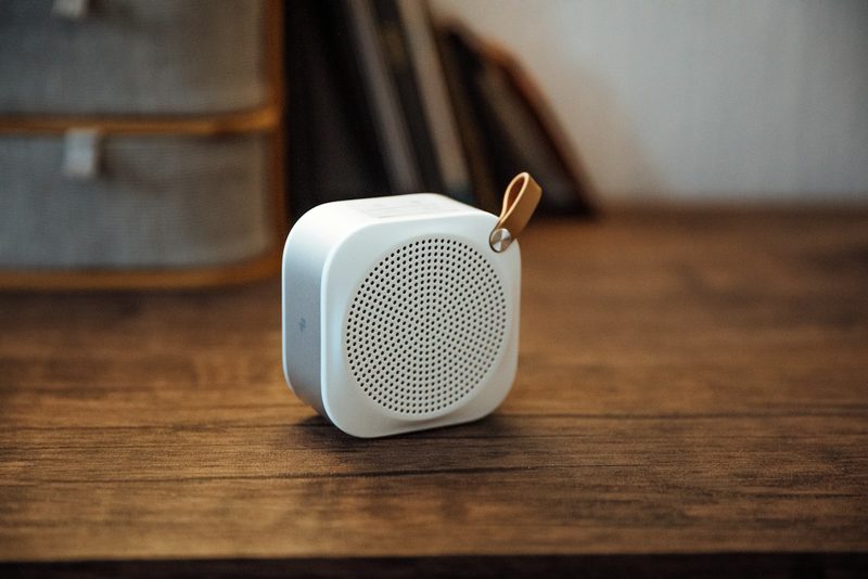 Small white portable speaker with a leather loop